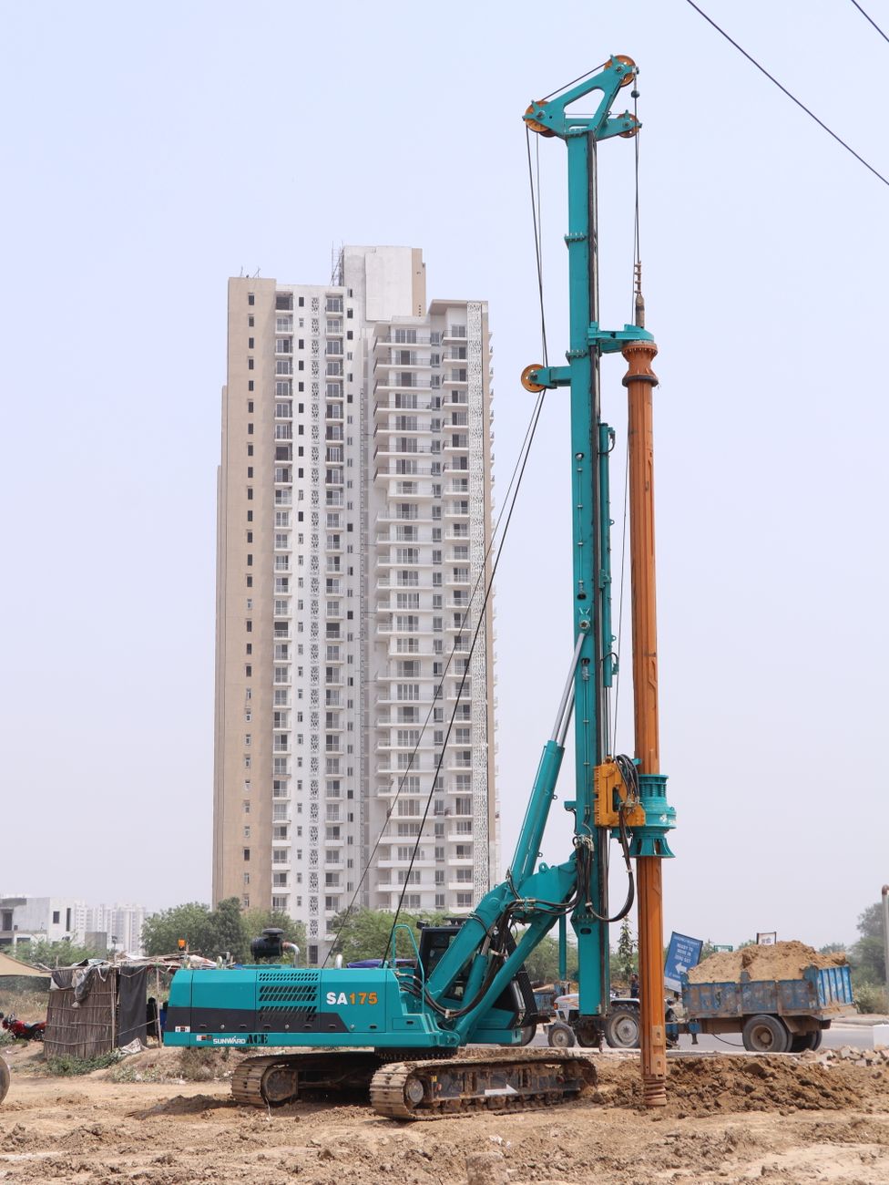 Piling rig installing a bored pile foundation adjacent to a high-rise building