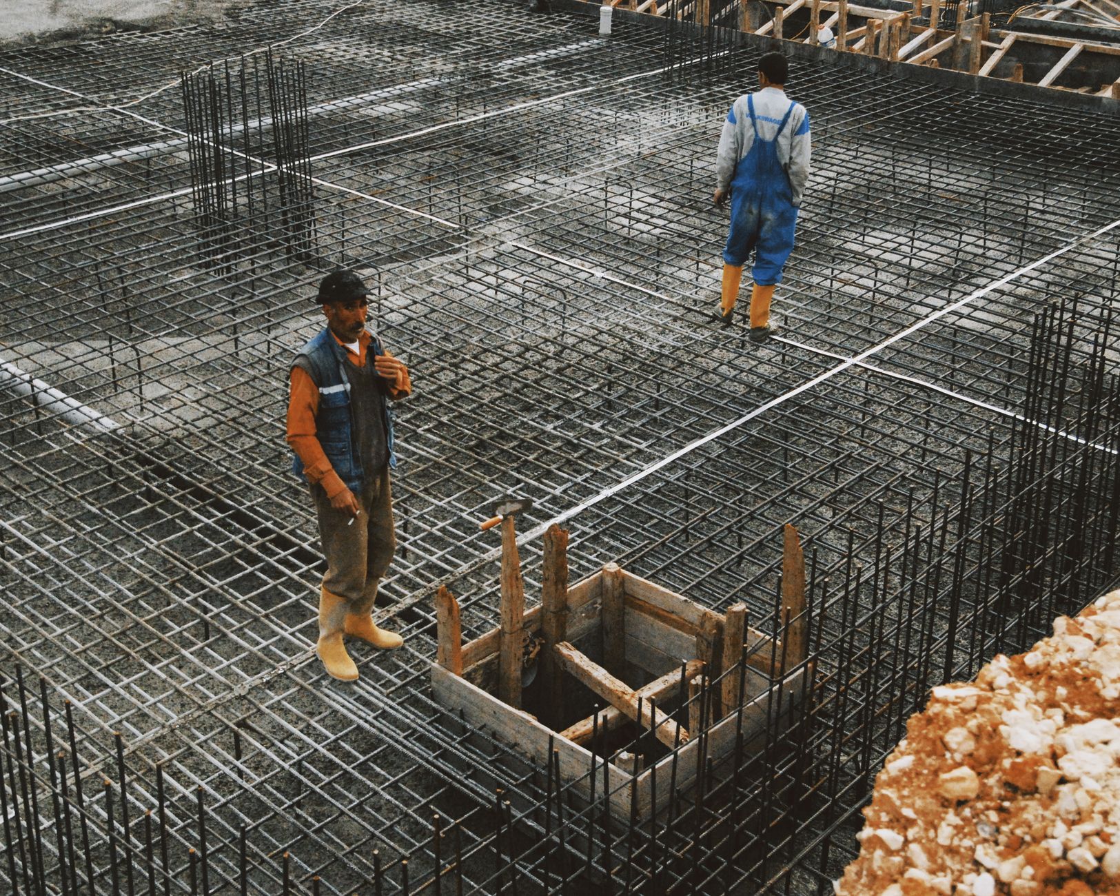 Workers preparing reinforcement mesh for a reinforced concrete pad foundation